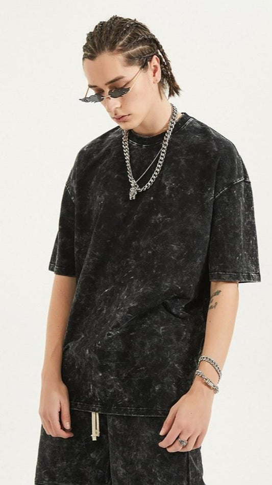Person wearing a black acid-wash t-shirt and sunglasses on a white background